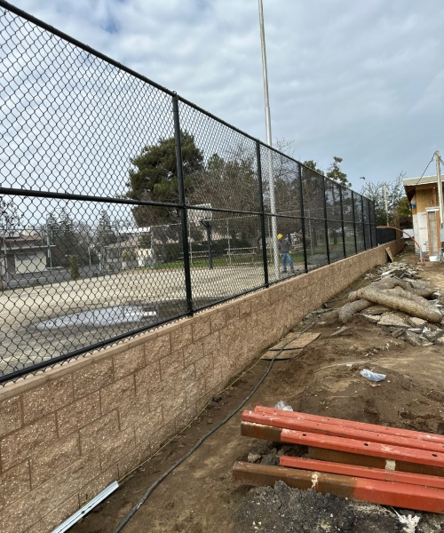 Commercial Fencing - Chain-link fence with a black coating, enclosing a construction area