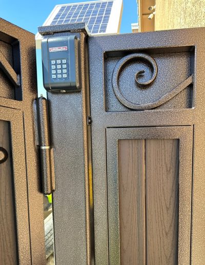 Black metal double gate with an arched top and decorative accents, equipped with an automatic opener