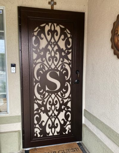 Close-up of a metal door with an intricate design and a monogram
