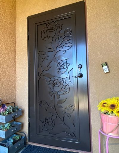 View of a metal security door with a decorative cut-out and a personalized monogram