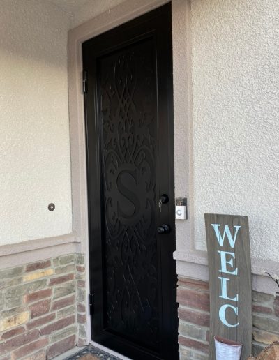 Metal door with an ornate design and a monogram, adding a touch of elegance to the entrance