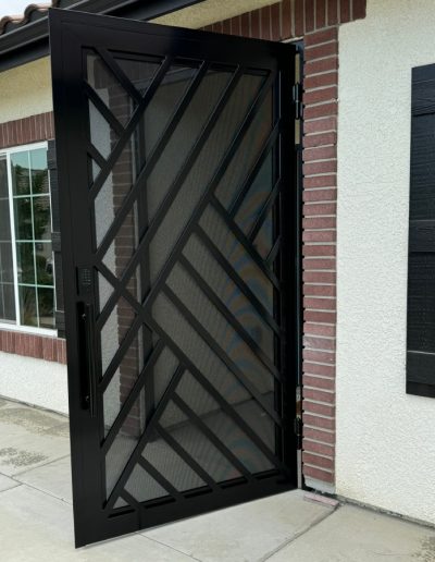 Custom-made metal security door with a decorative monogram and intricate cut-outs