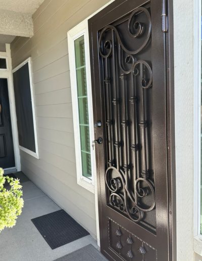 Ornate metal security door with a personalized monogram and a decorative pattern