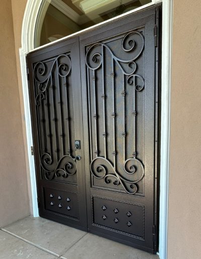 Metal security door with a monogram and an intricate design, creating a welcoming and inviting entrance