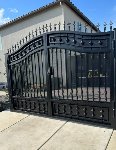 Black double driveway gate with ornate metalwork and decorative accents