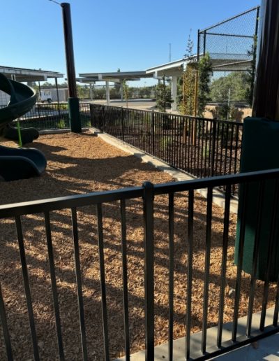 Black metal fence with vertical bars, creating a secure enclosure for a small outdoor area