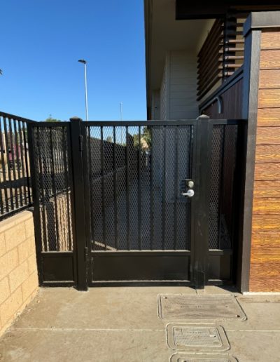 Black metal fence with a gate, offering a safe and stylish enclosure for a backyard or patio