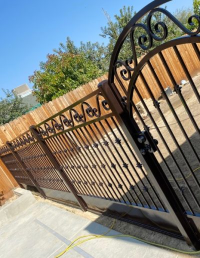 Ornate metal fence with a decorative gate featuring intricate scrollwork and a dark finish